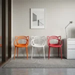 Outdoor stackable plastic chair featuring a weather-resistant molded polypropylene plastic body with an intricate interlocking loop backrest and integrated armrests, a contoured seat pan, and a space-saving stackable structure available in orange, white, and red finishes, supported by four integrated tapered legs with non-marking floor glides.