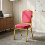 High quality red banquet chair featuring a crown-back profile with red fabric upholstered backrest and a high-density cushioned seat pan, a stackable armless frame design with protective stacking bumpers, and a gold powder-coated square steel tube four-leg base with non-marring floor glides.