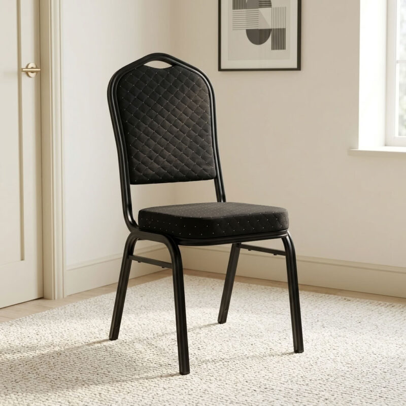 Stackable black fabric event chair featuring diamond-quilted black fabric upholstery with subtle flecked pattern details, a high-density padded crown-back backrest with integrated top handhold cut-out and thick cushioned seat, armless space-saving configuration, stackable design with side frame bumpers, and a heavy-duty black powder-coated tubular steel four-legged frame equipped with protective floor glides. Stackable black fabric event chair featuring diamond-quilted black fabric upholstery with subtle flecked pattern details, a high-density padded crown-back backrest with integrated top handhold cut-out and thick cushioned seat, armless space-saving configuration, stackable design with side frame bumpers, and a heavy-duty black powder-coated tubular steel four-legged frame equipped with protective floor glides.