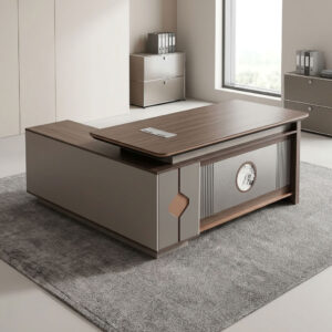 1.8m executive office table featuring a walnut wood grain laminate desktop with bevel-trimmed edges and grey side paneling, an L-shaped return cabinet structure with integrated storage compartments, a front modesty panel with fluted detailing and a central decorative emblem, built-in desktop flip-top cable management grommet, and a heavy-duty full-plinth base with floor-protective glides.